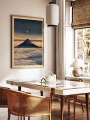 Japanese art print of Mount Fuji rising above clouds with a glowing full moon in a deep blue and, in a styled room mockup