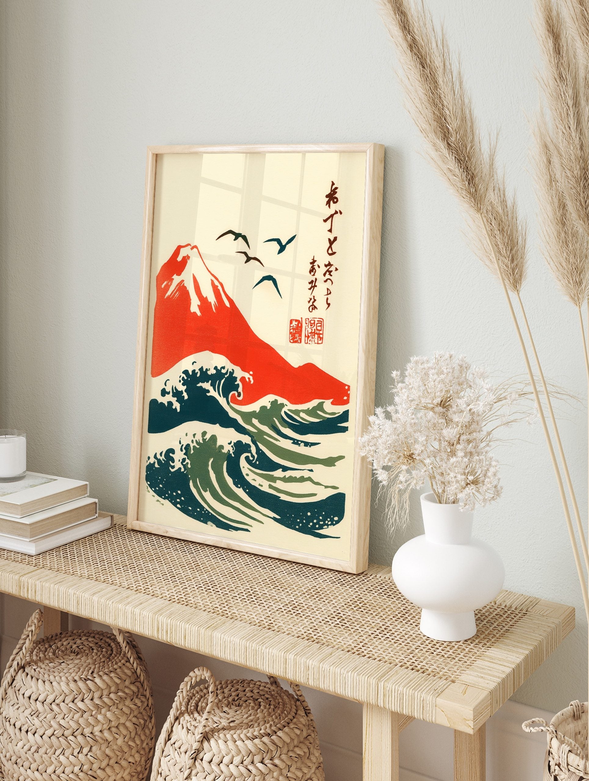 Japanese woodblock style art print of red Mount Fuji, dark blue and green ocean waves, and, in an alternate framed mockup