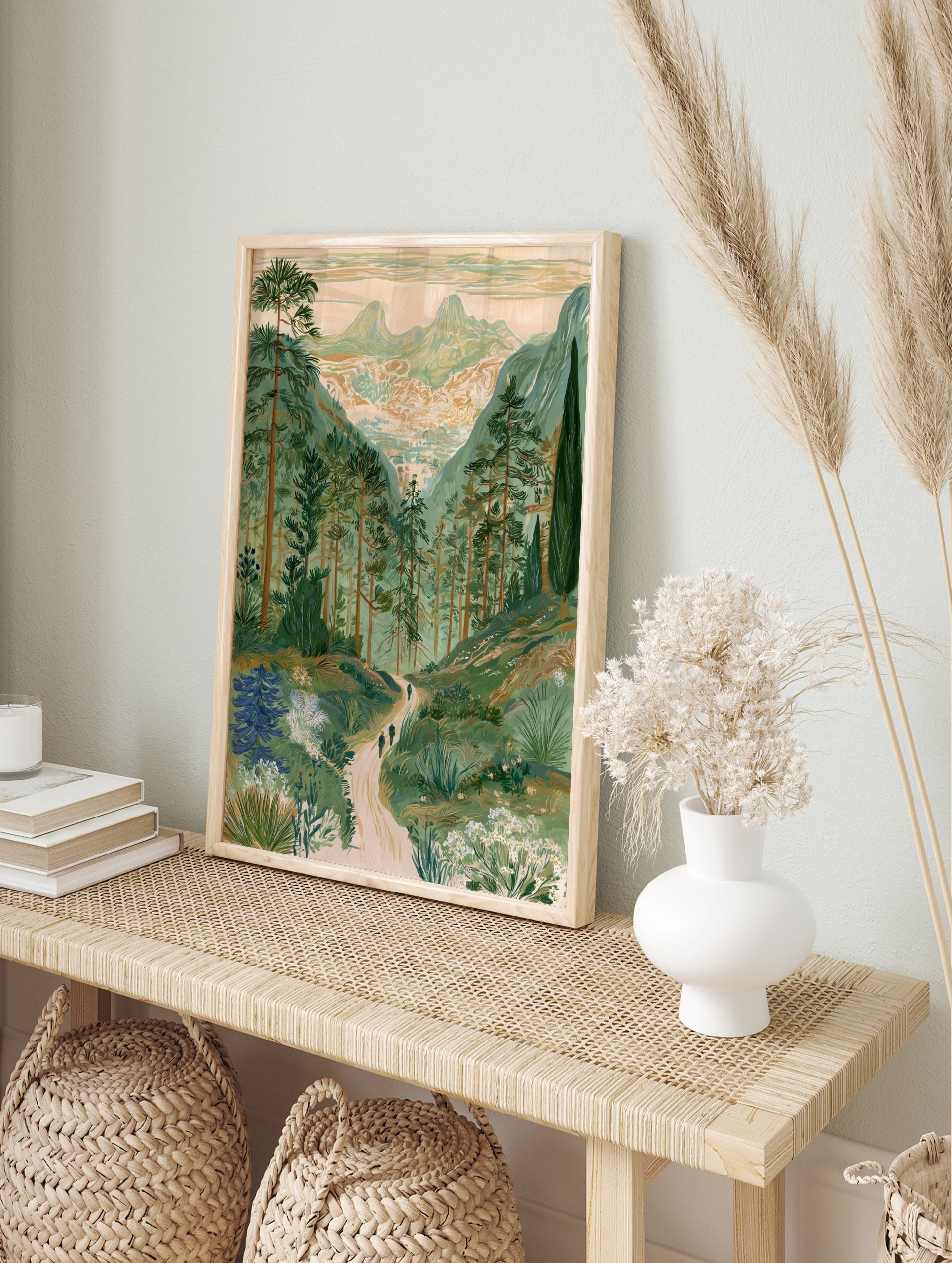 Illustrative mountain valley landscape print with pine trees, a winding path, and twin peaks, in an alternate framed mockup