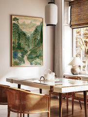 Illustrative mountain valley landscape print with pine trees, a winding path, and twin peaks in a, in a styled room mockup