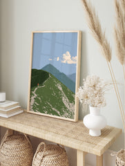 Illustrative mountain ridge wall art with a hiker wearing a red backpack on a green grassy, in an alternate framed mockup