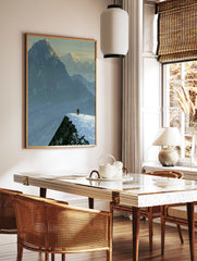 Illustrative mountain landscape art print showing a lone skier on a snowy ridge against a backdrop, in a styled room mockup
