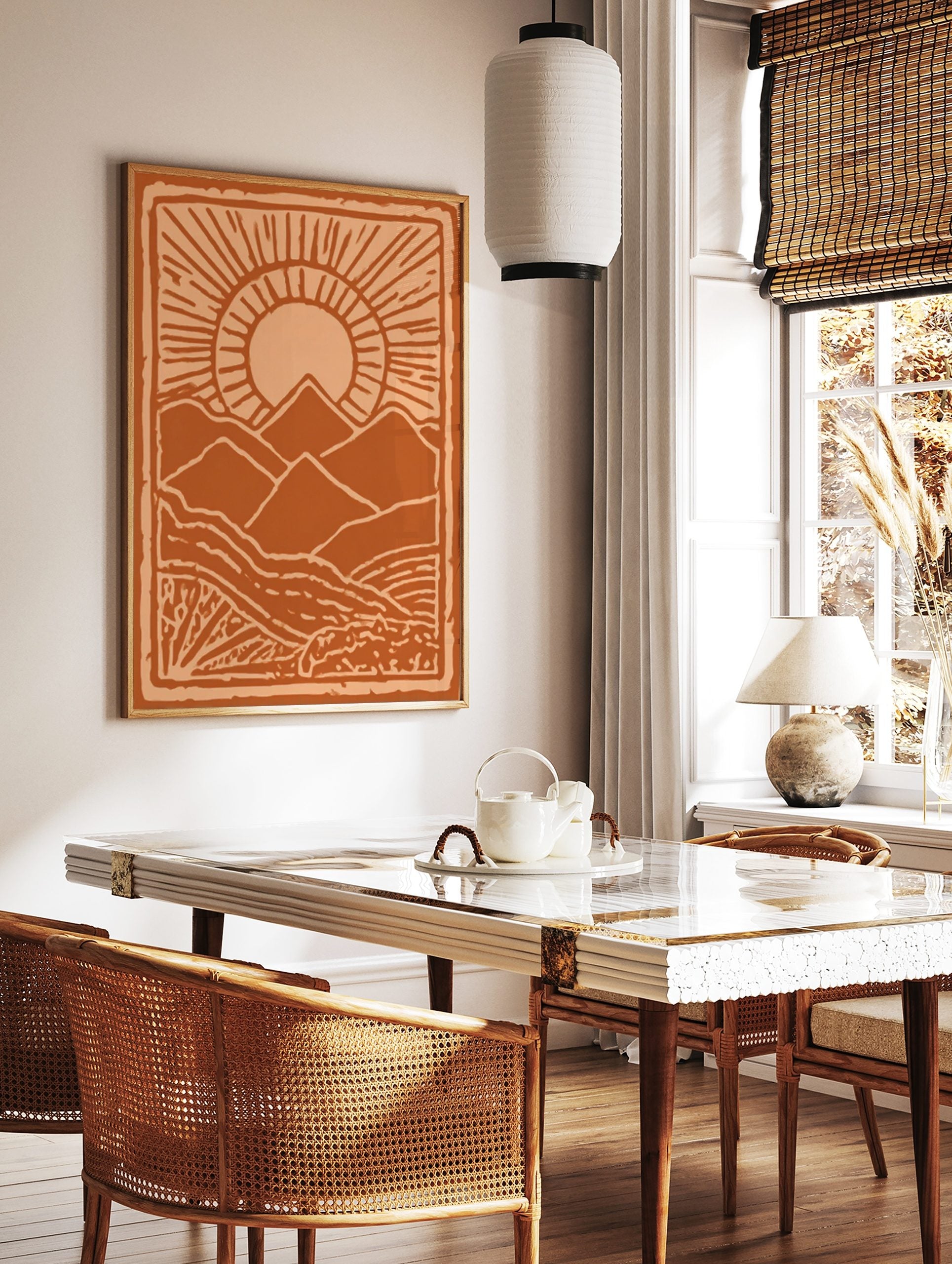 Stylised orange mountain landscape art print with a radiant sun and textured foreground, framed by, in a styled room mockup