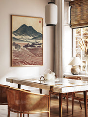 Woodblock print of navy mountains, red terraced fields, and houses in a rustic village landscape, in a styled room mockup