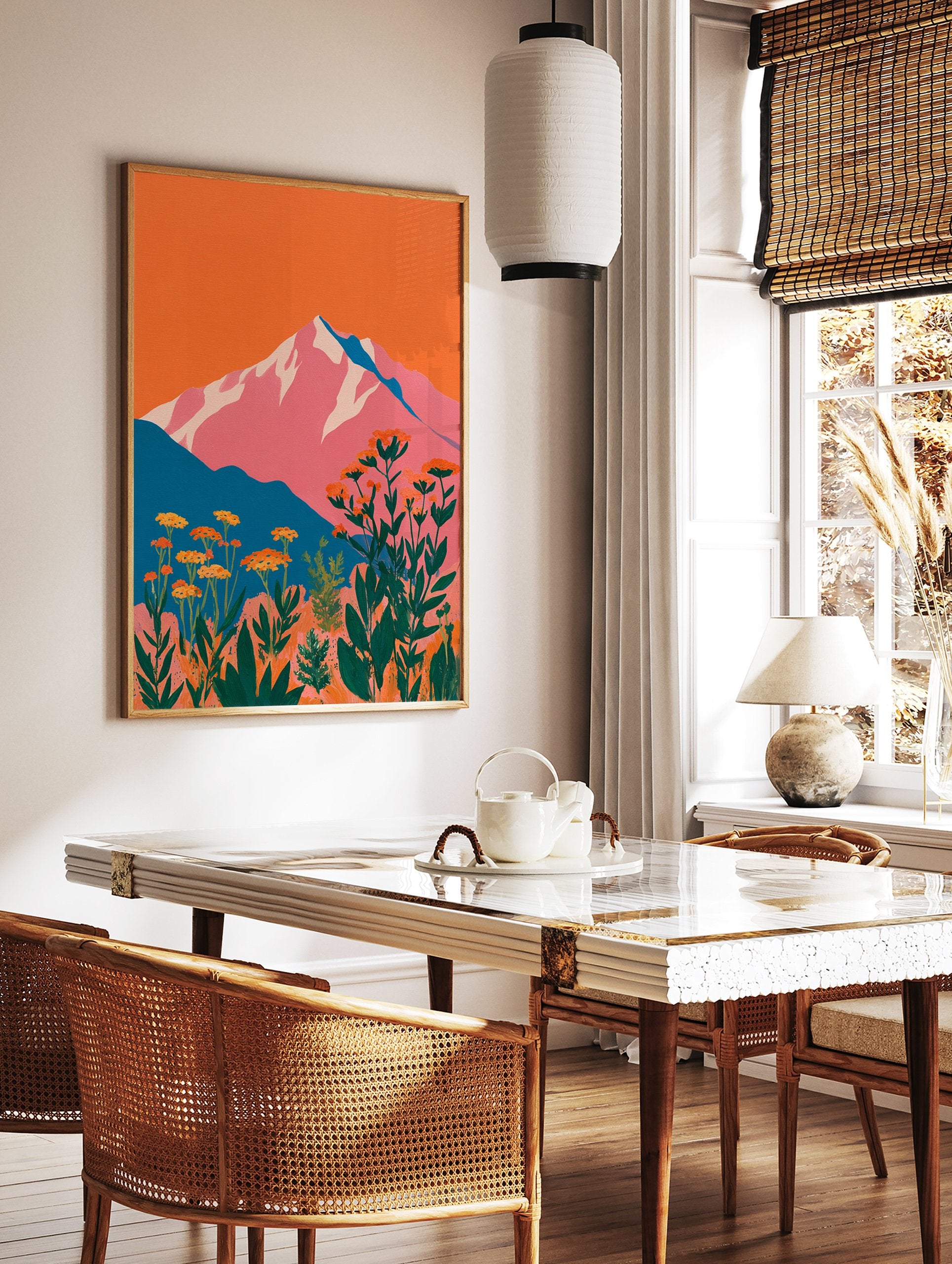 Vibrant mountain wall art with pink peaks, orange sky, teal hills, and foreground of orange botanical flowers and green leaves. - Image 2
