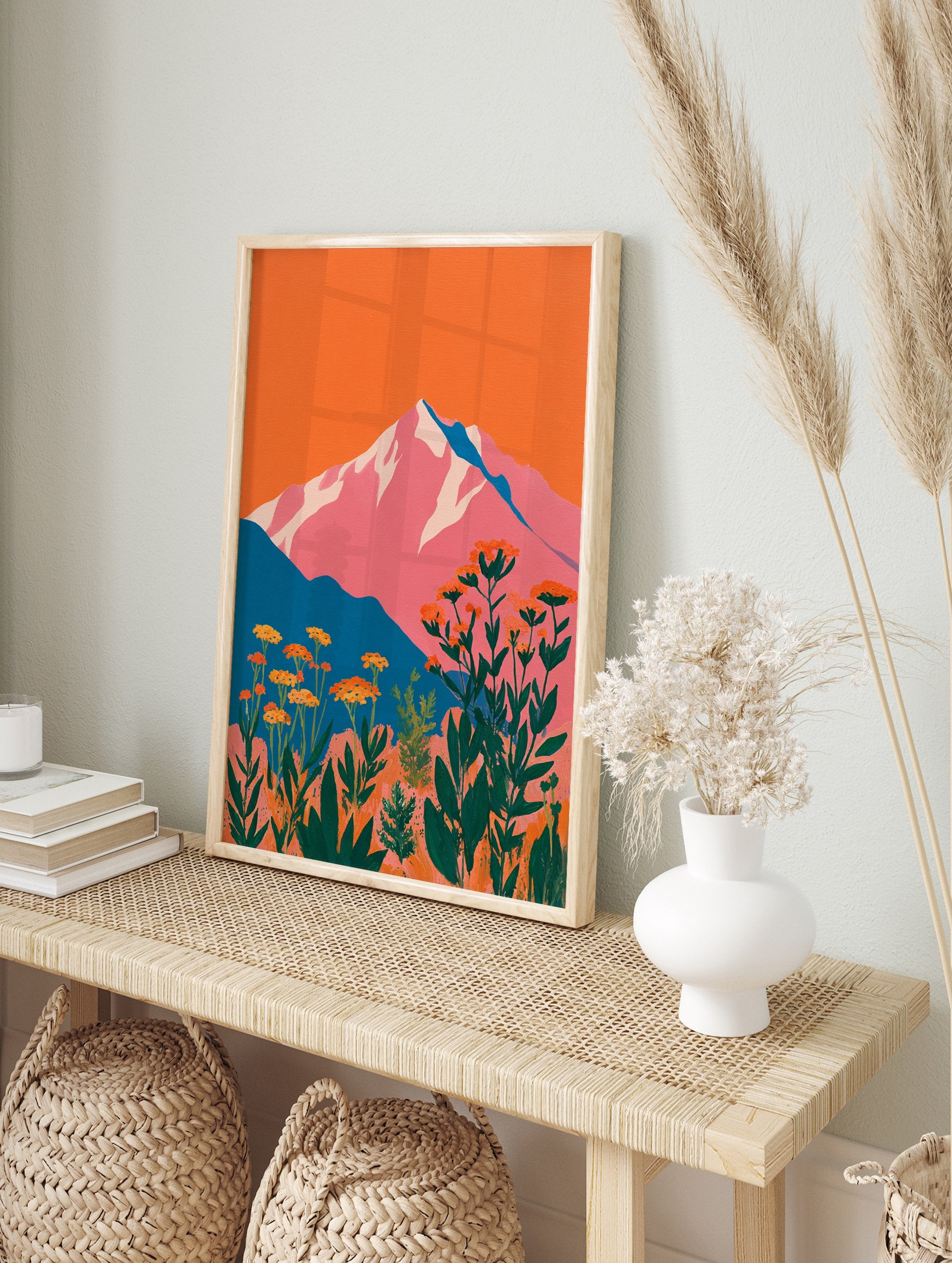 Vibrant mountain wall art with pink peaks, orange sky, teal hills, and foreground of orange botanical flowers and green leaves. - Image 3