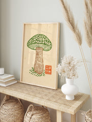Green mushroom woodcut print with mottled cap and brown stem, orange Japanese character seal, in an alternate framed mockup