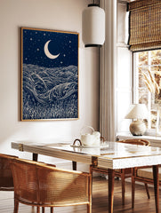 Stylised night ocean illustration with swirling waves, a crescent moon, stars, and grass, in dark, in a styled room mockup