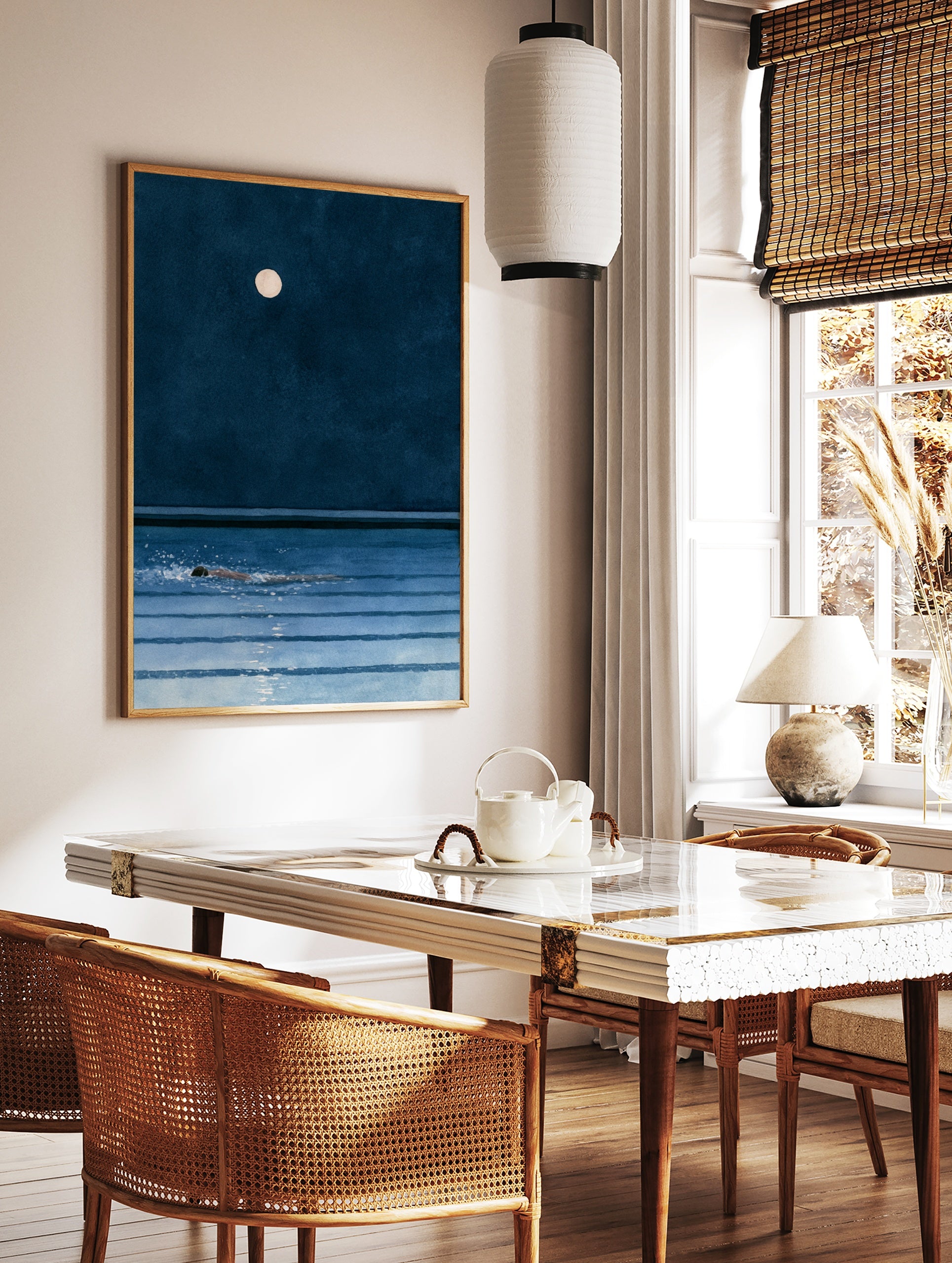 Minimalist art print of a person swimming in dark blue water under a full moon at night, in a styled room mockup