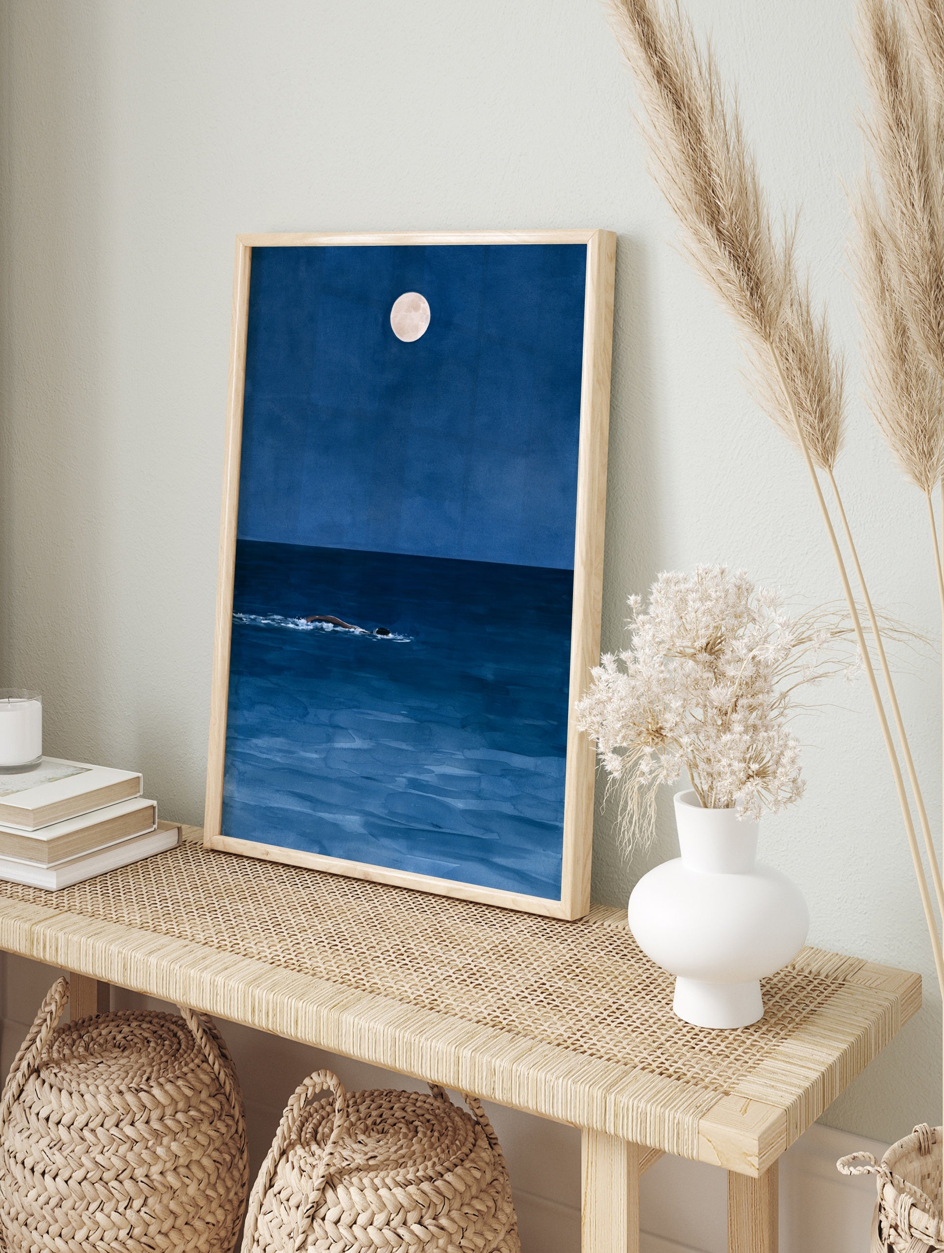 Minimalist art print of a person swimming in a deep blue ocean at night under a full moon, in an alternate framed mockup