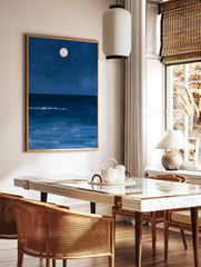 Minimalist art print of a person swimming in a deep blue ocean at night under a full moon, in a styled room mockup
