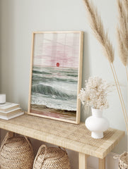 Ocean sunset watercolour and line art print with red sun, green waves, and sandy beach, in an alternate framed mockup