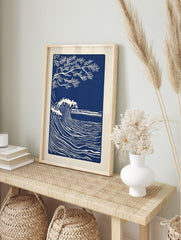 Illustrative deep blue and white art print of a large ocean wave and a tree branch, in an alternate framed mockup