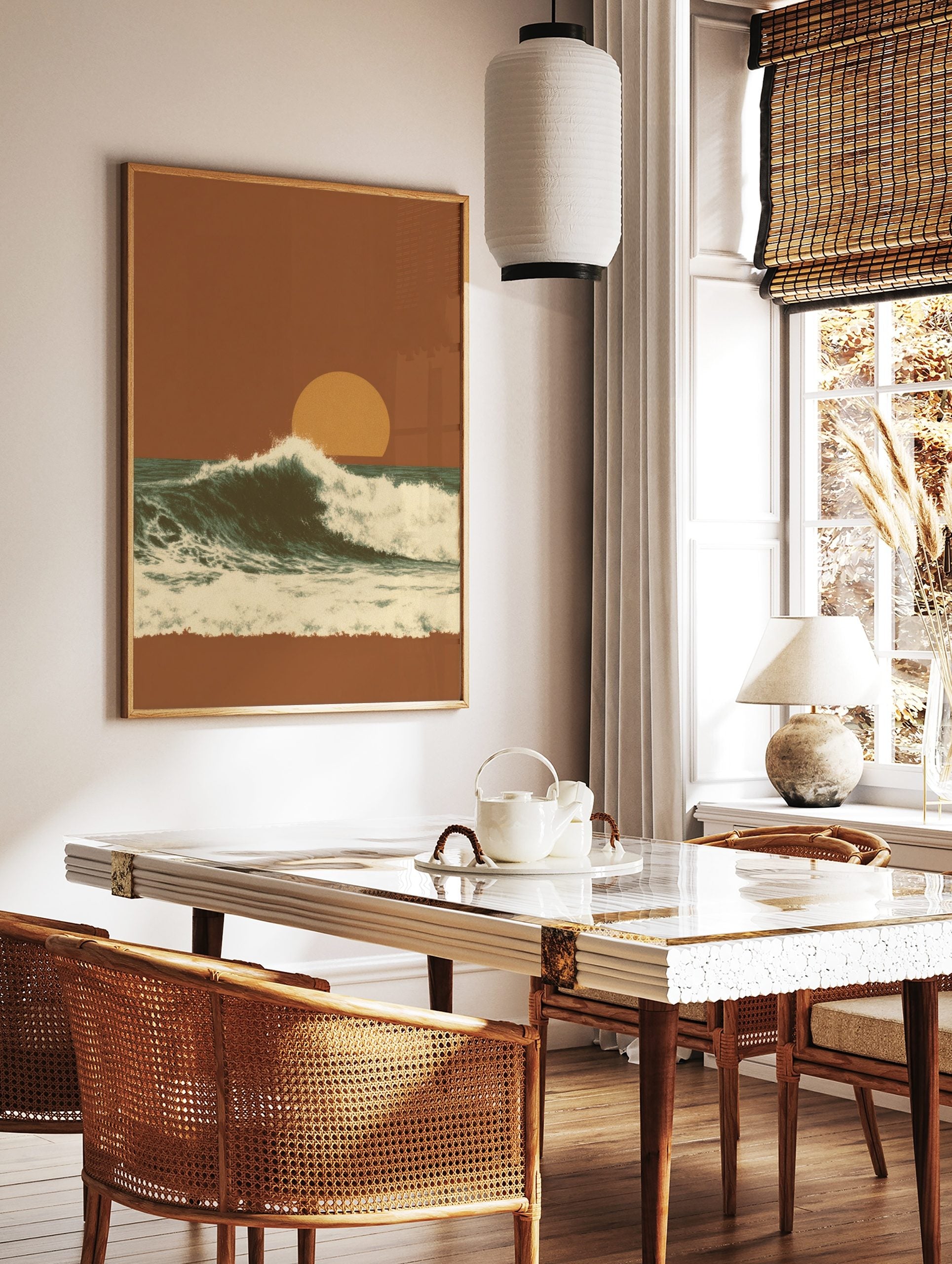 Illustrative ocean wave crashing against a dark teal sea under an orange sunset sky with a large sun, in a styled room mockup