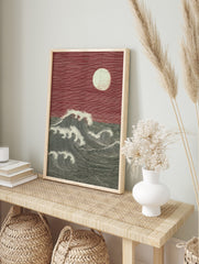 Woodcut style print of large ocean waves and full moon against a red sky, with strong lines, in an alternate framed mockup