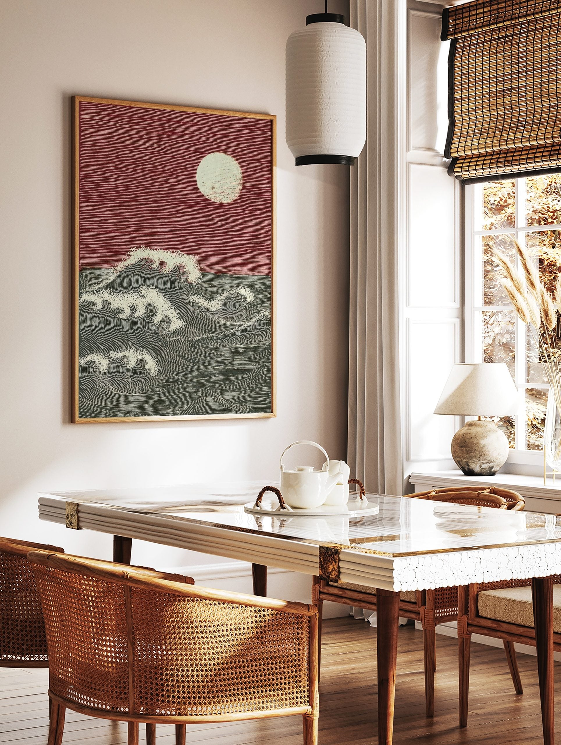 Woodcut style print of large ocean waves and full moon against a red sky, with strong lines, in a styled room mockup