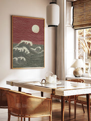 Woodcut style print of large ocean waves and full moon against a red sky, with strong lines, in a styled room mockup