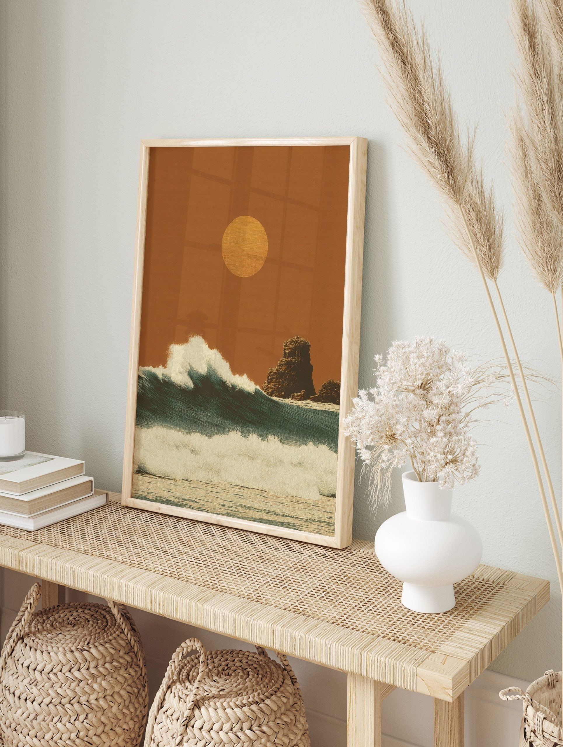 Stylised ocean waves under a warm orange sun with rock formations in a textured, illustrative, in an alternate framed mockup