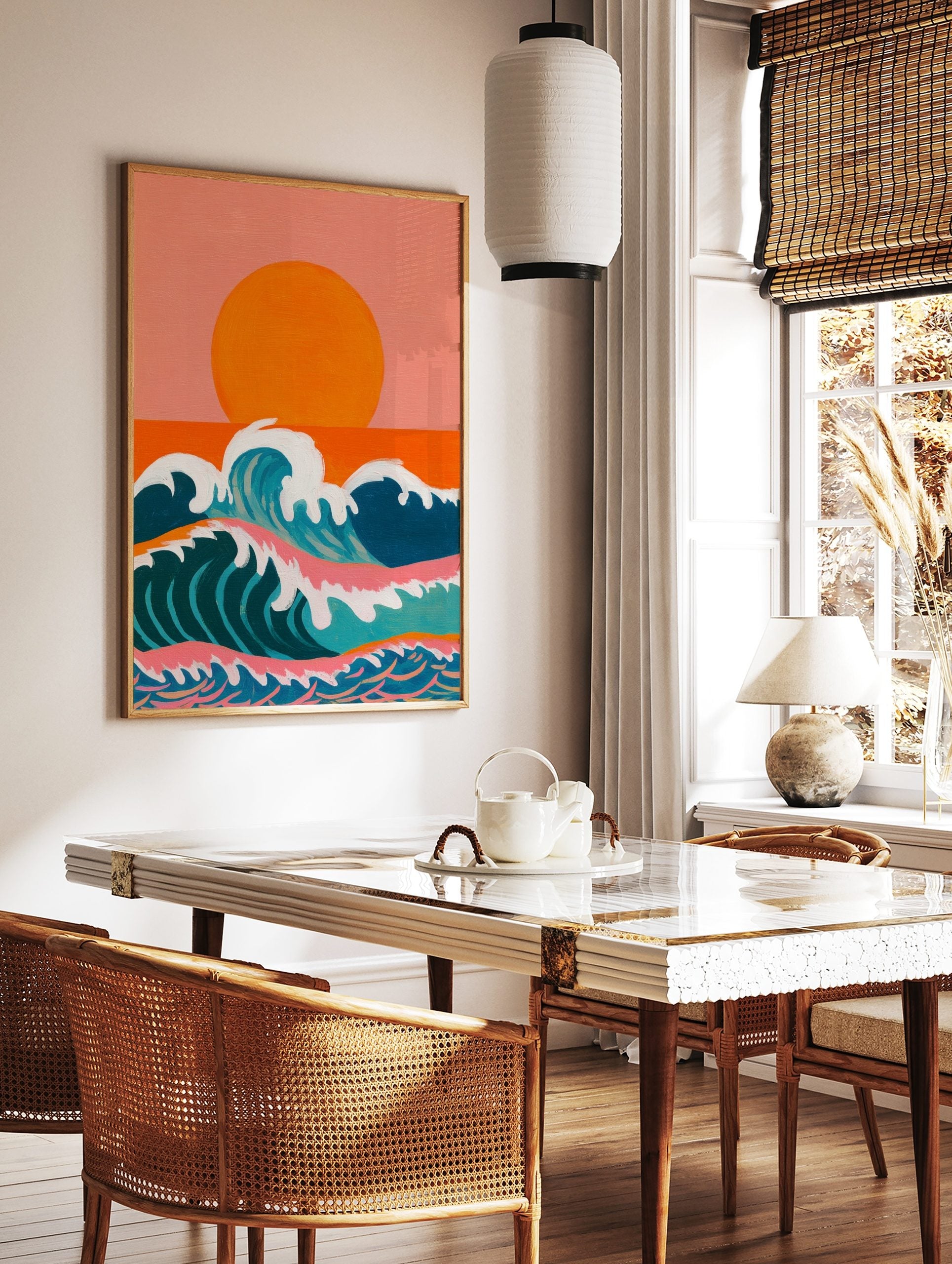 Illustrative ocean waves with white foam under a large orange sun and peachy-pink sky, in a styled room mockup