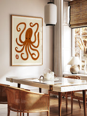 Minimalist brown octopus illustration with brush-stroke texture and a small red seal mark on a, in a styled room mockup