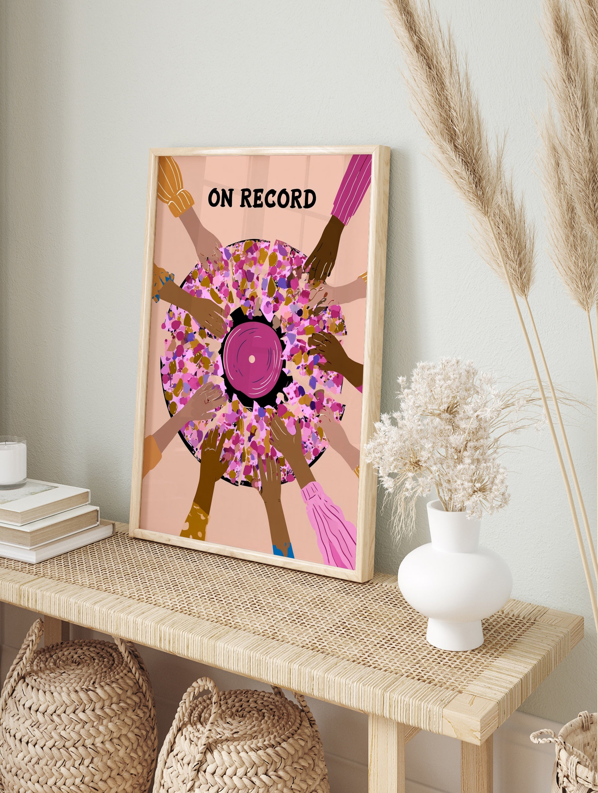 Illustrative wall art of a vinyl record surrounded by hands with ON RECORD text in pink, in an alternate framed mockup