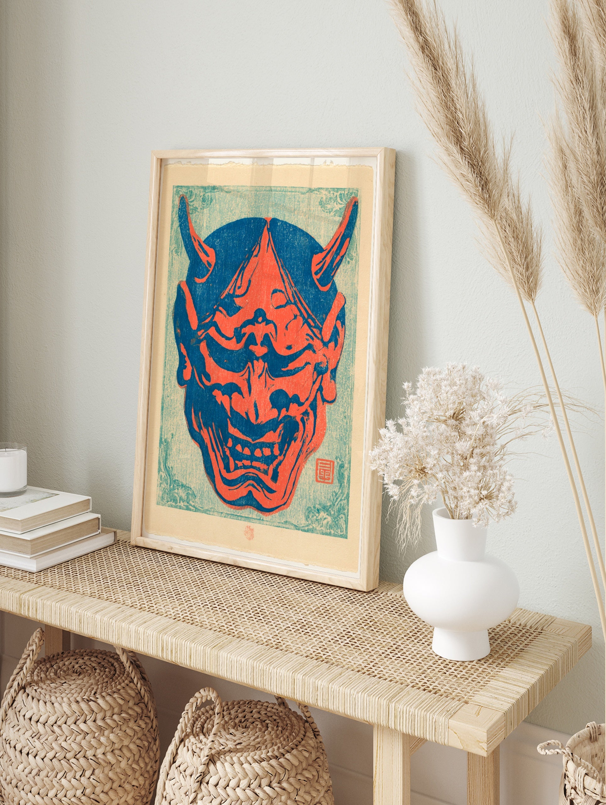 Japanese Oni mask illustration in bold red and blue colours, featuring sharp horns and bared, in an alternate framed mockup