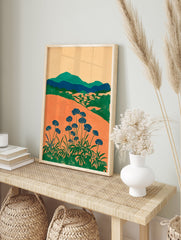 Modern botanical wall art print with orange fields, green mountains, and blue flowers on long stems against a light background. - Image 3