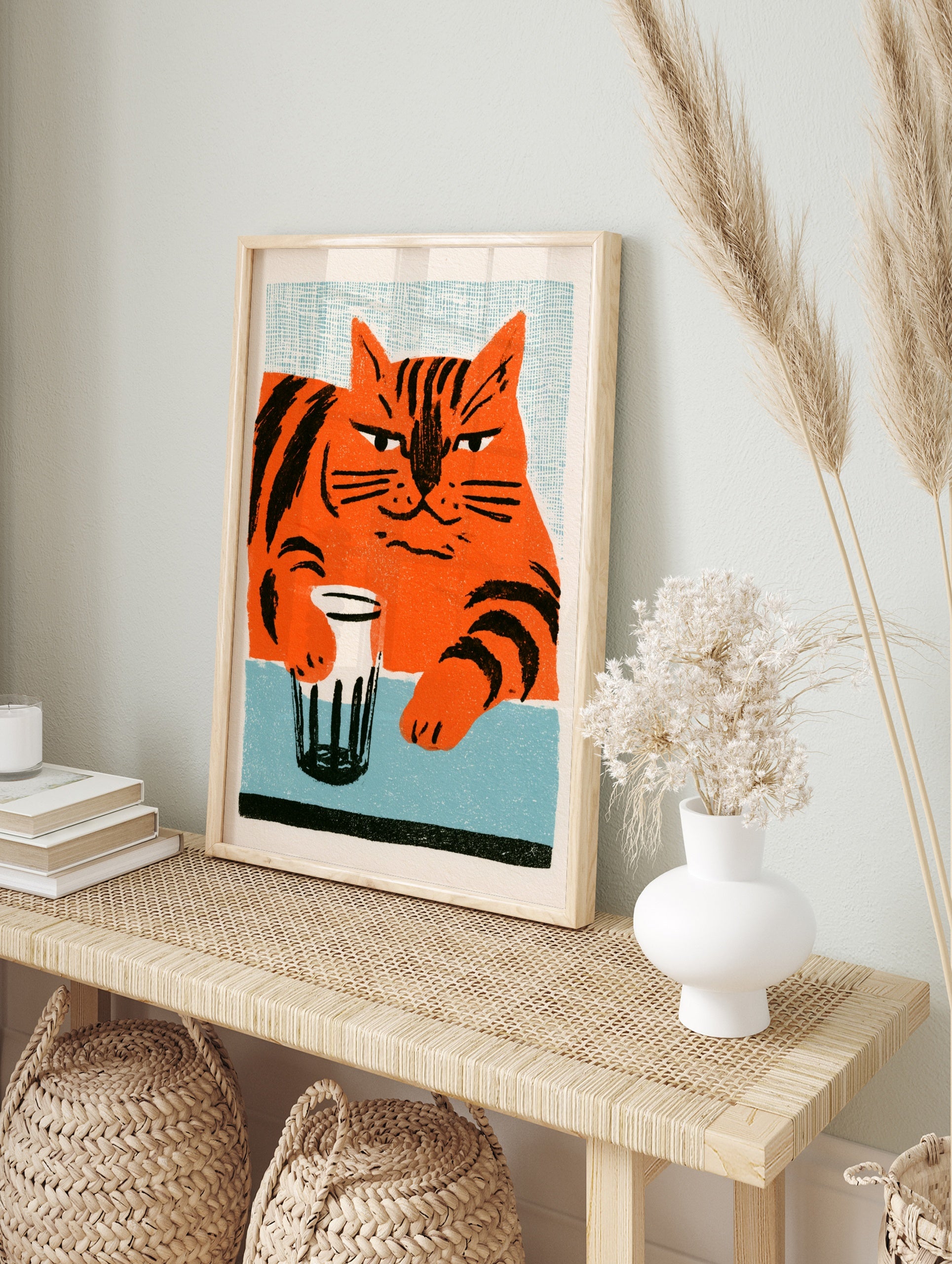 Stylised orange cat with black stripes holding a glass on a blue table, illustrative wall art, in an alternate framed mockup
