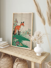 Illustrative print of an orange fox standing in green grass with colourful wildflowers on a, in an alternate framed mockup