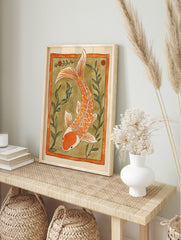 Orange koi fish illustration with white accents, swimming amidst green aquatic plants within, in an alternate framed mockup