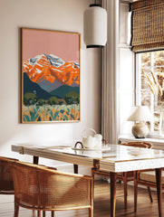 Illustrative landscape art print of orange snow-capped mountains, teal hills, and wildflower meadow, in a styled room mockup