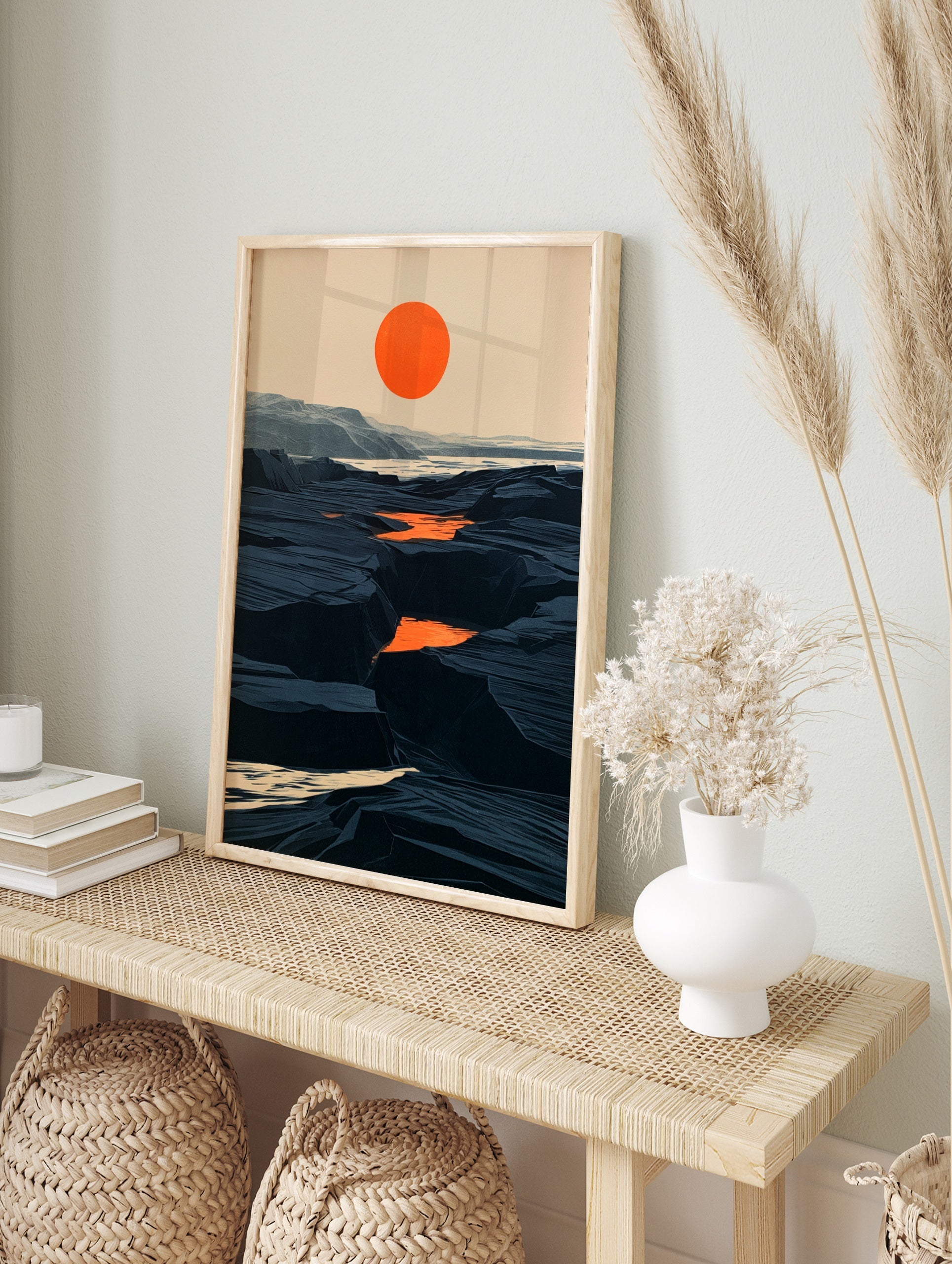 Minimalist landscape art print with a bold orange sun over a dark, rocky canyon terrain in, in an alternate framed mockup