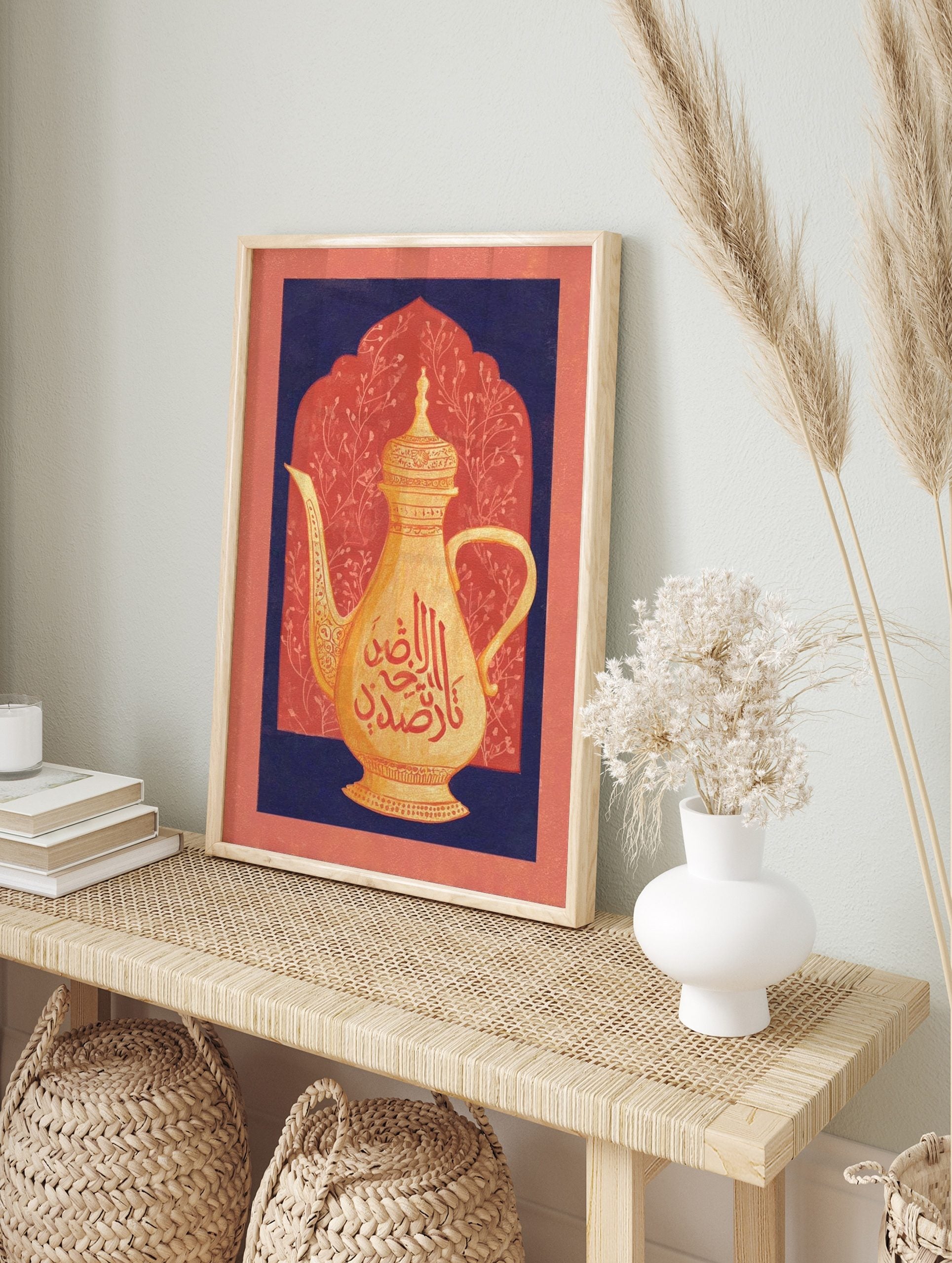 Golden Arabic coffee pot with red calligraphy against a coral arched background framed by, in an alternate framed mockup