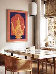 Golden Arabic coffee pot with red calligraphy against a coral arched background framed by navy blue, in a styled room mockup