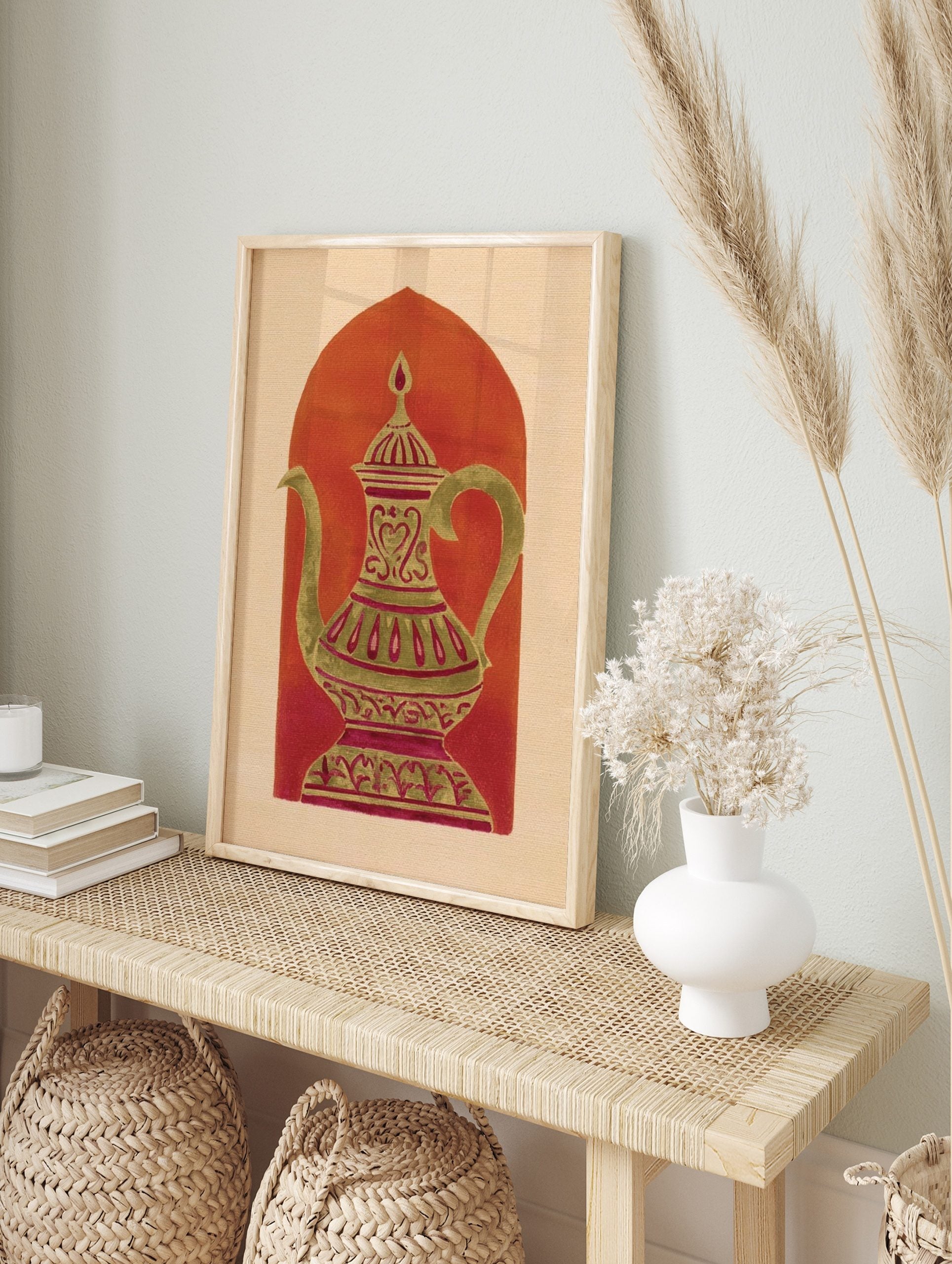 Ornate gold-green coffee pot with magenta patterns against a reddish-orange arch on a beige, in an alternate framed mockup