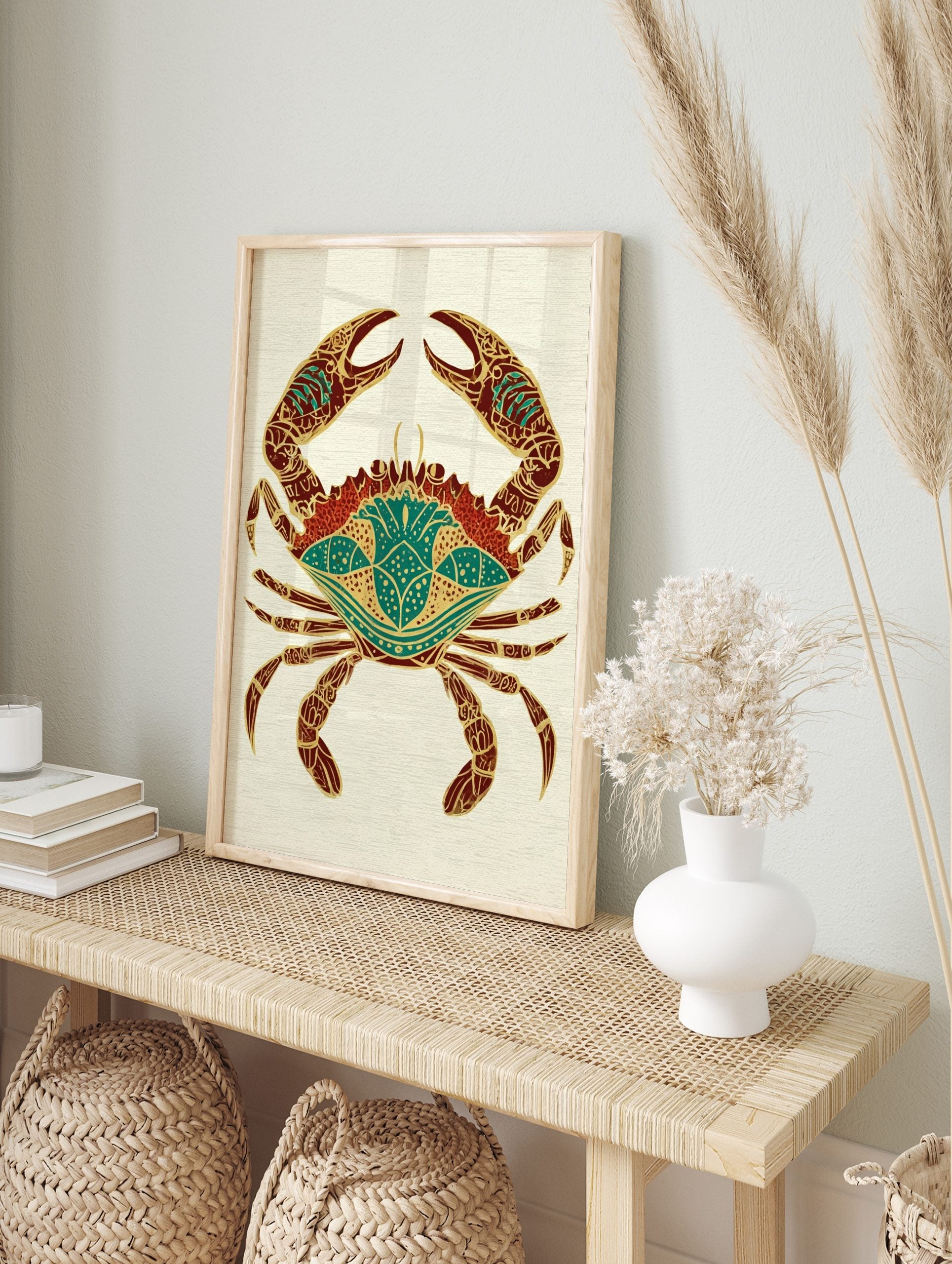 Ornate crab illustration with gold patterns on red and teal body on a light textured, in an alternate framed mockup