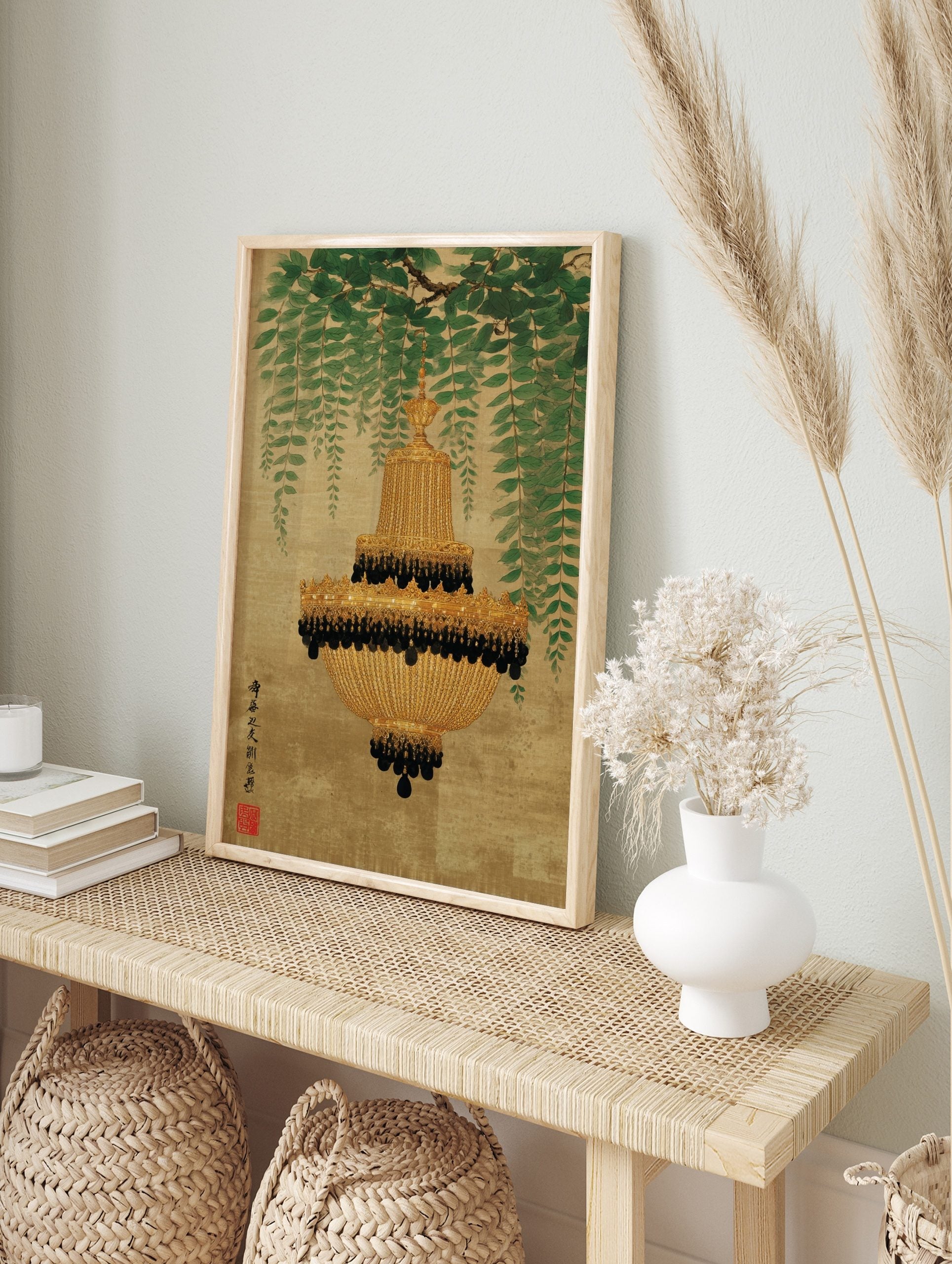 Ornate gold chandelier with black beads hanging from a branch with weeping green leaves on a, in an alternate framed mockup