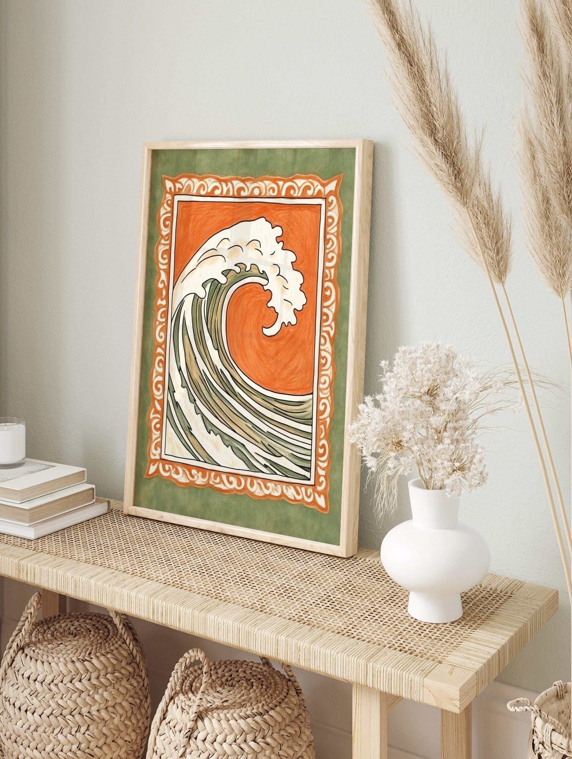 Stylised ocean wave illustration with white foam, orange background, and ornate green border, in an alternate framed mockup