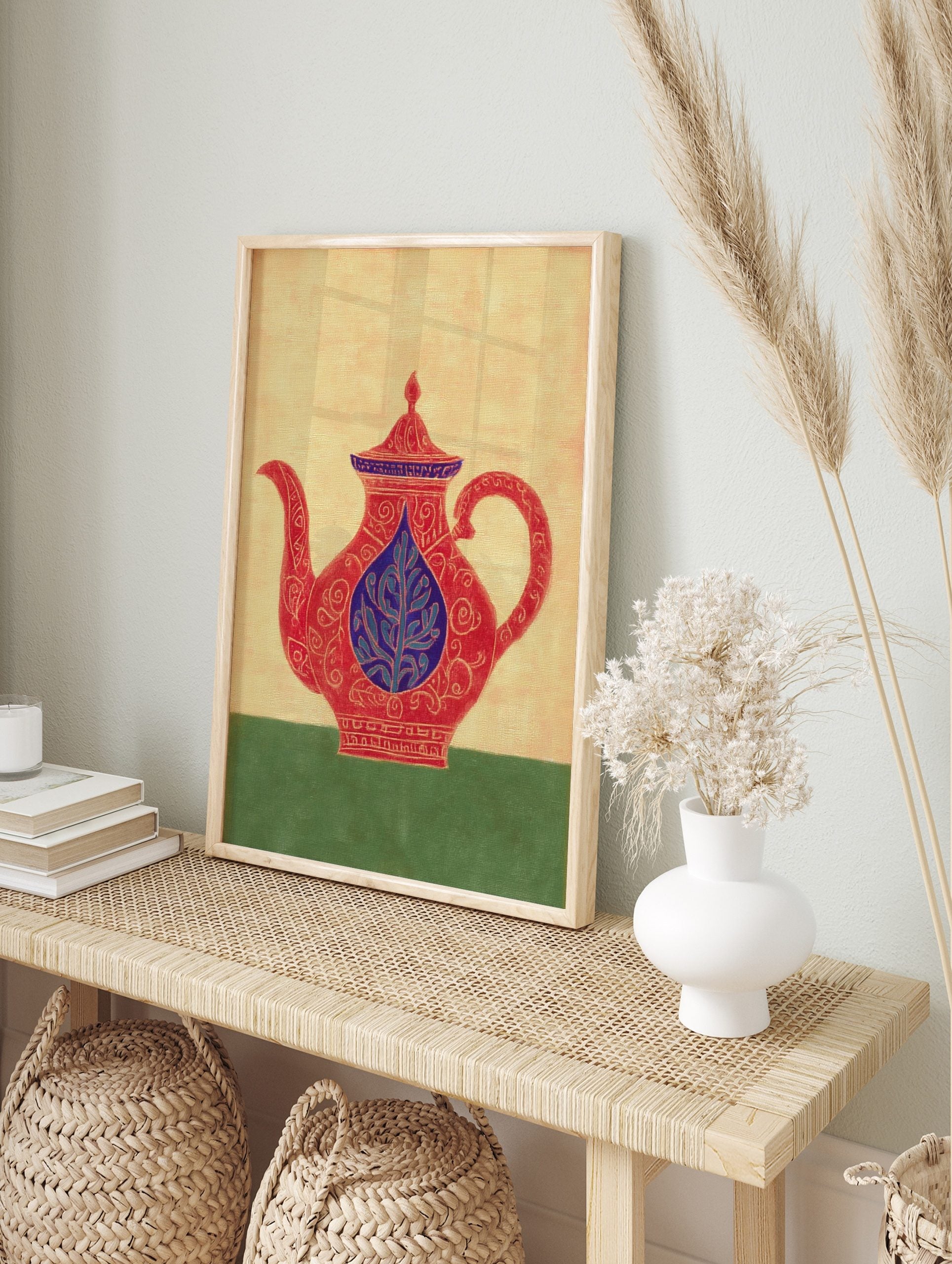 Ornate red teapot illustration with blue lid and central leaf motif, on a beige background, in an alternate framed mockup