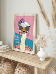 Quirky ostrich wall art wearing sunglasses and flowers, with 'Hello Sweet Cheeks' text on a pink and teal background, displayed as the same artwork in an alternate framed wall art mockup