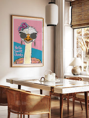 Quirky ostrich wall art wearing sunglasses and flowers, with 'Hello Sweet Cheeks' text on a pink and teal background, displayed as the same artwork in a styled poster mockup for home decor