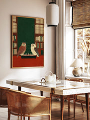 Illustrative print of a tawny owl and a white owl playing chess on a red table, flanked by, in a styled room mockup