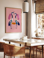 Two stylised cranes with navy, white, teal plumage on a pink background, facing each other, in a styled room mockup