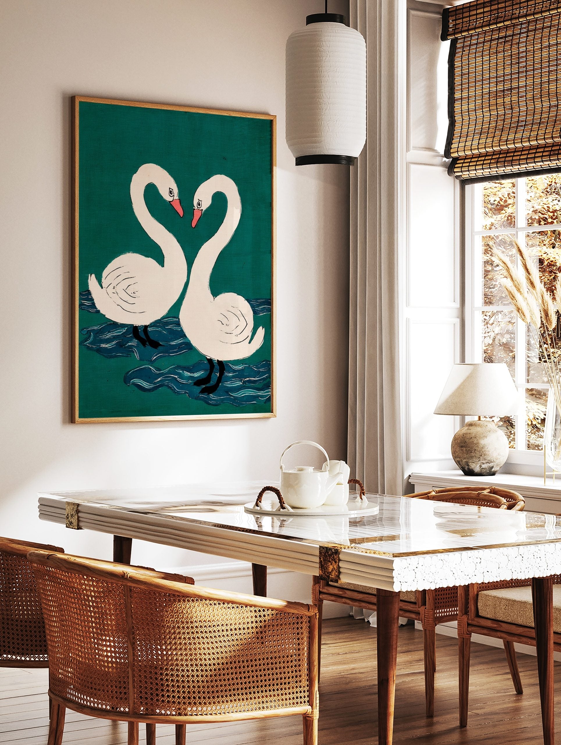Two white swans with pink beaks form a heart shape against a teal-green background with blue water, in a styled room mockup