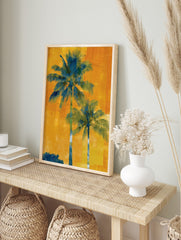 Two tall blue-green palm trees against a vibrant, textured orange and yellow background in a, in an alternate framed mockup