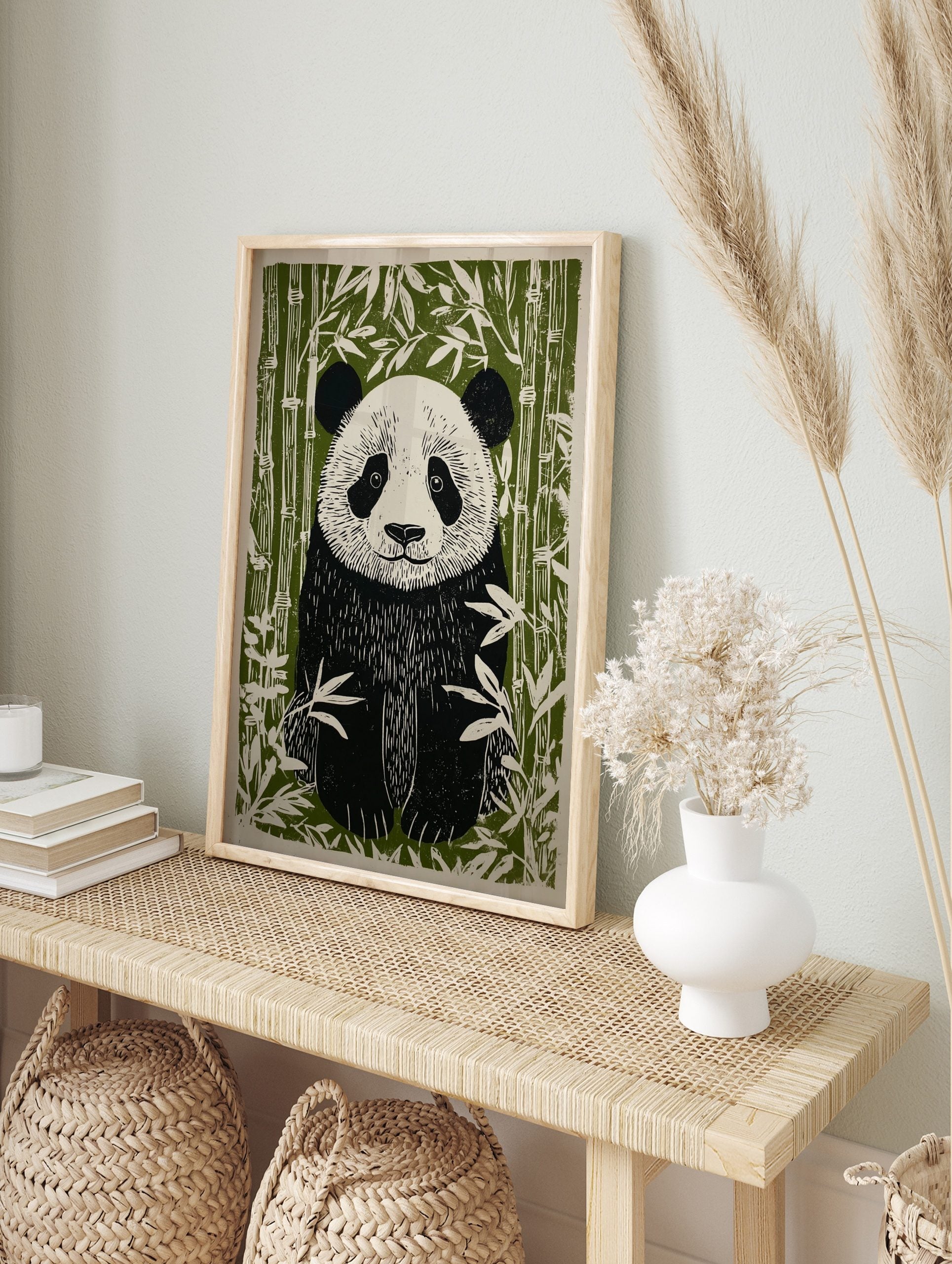 Linocut style illustration of a giant panda sitting among green bamboo stalks and leaves, in an alternate framed mockup