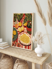Illustrative still life print of pasta, sliced citrus fruits, and green potted plants on a, in an alternate framed mockup