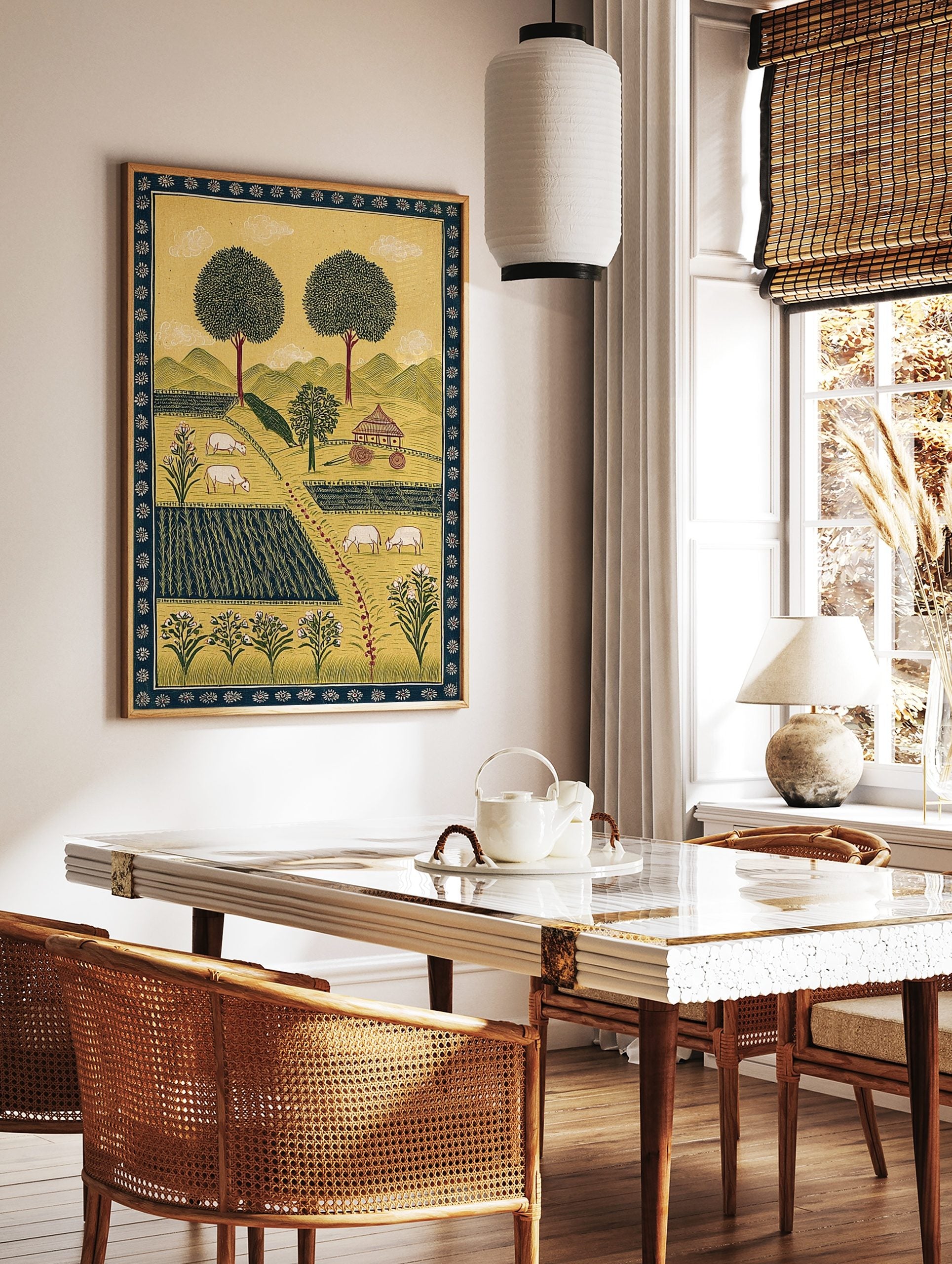 Folk art pastoral landscape print with trees, green hills, hut, fields, and white sheep grazing, in a styled room mockup