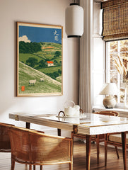 Japanese-style illustrative pastoral landscape art print featuring sheep on green hills and a, in a styled room mockup