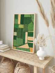 Aerial view of green and beige patchwork farmland fields, illustrative landscape wall art, in an alternate framed mockup